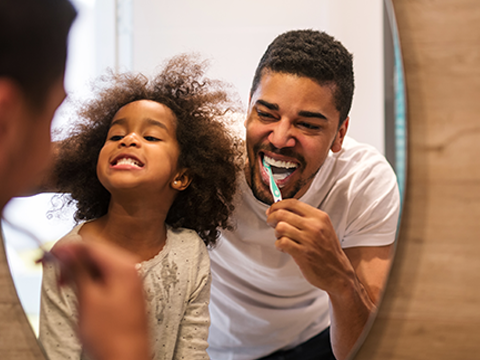 Man brushing teeth with daughter